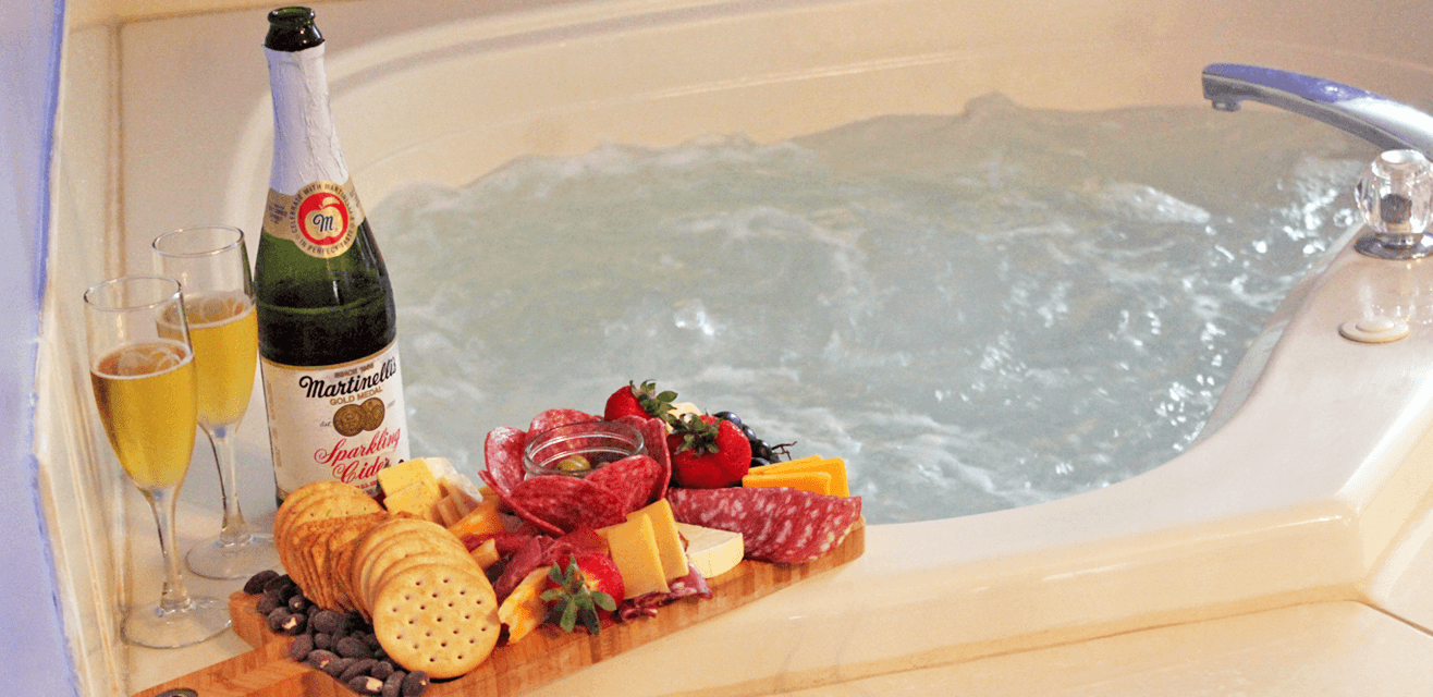 Champagne, cheese, and crackers on a board beside a bubbling hot tub, creating a luxurious, relaxing atmosphere.