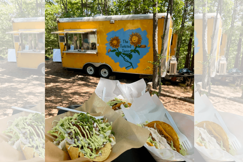 A vibrant yellow food truck named "The Twisted Taco" with tacos displayed in front, set in a wooded area.