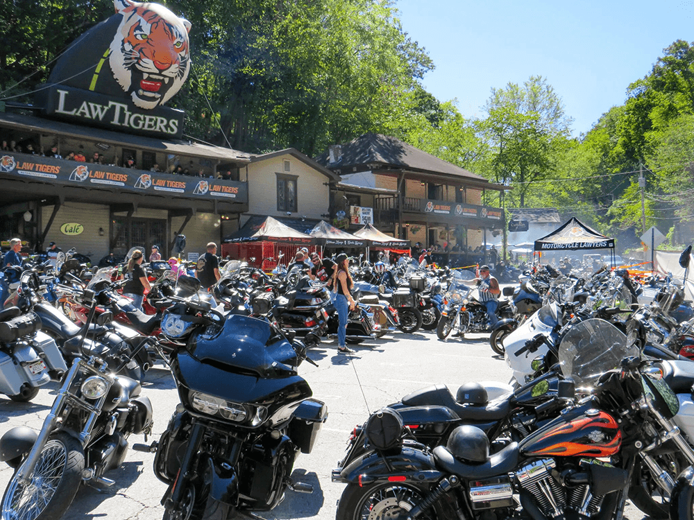 A crowded motorcycle rally outside a building with a large "Law Tigers" sign.