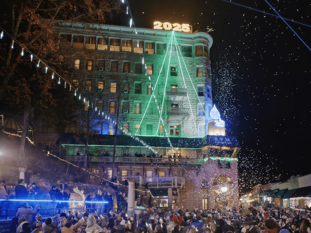 A festive crowd gathers outside a brightly lit hotel featuring a large "2025" display and decorative lights.