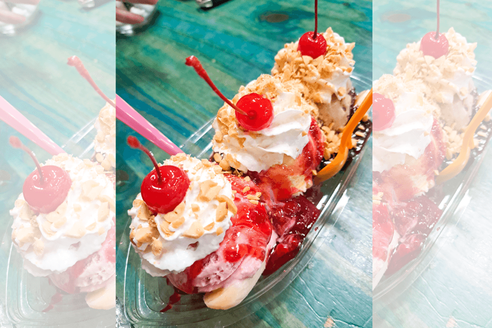 A colorful ice cream sundae topped with whipped cream, cherries, and nuts, served in a clear dish.